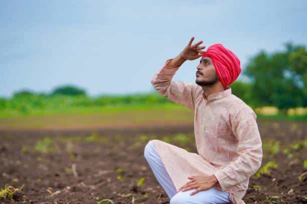 Indian man in traditional clothing sitting in a field, waiting for the rains in monsoon 2025